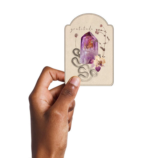 Model's hand holds the Gratitude Gemstone sticker