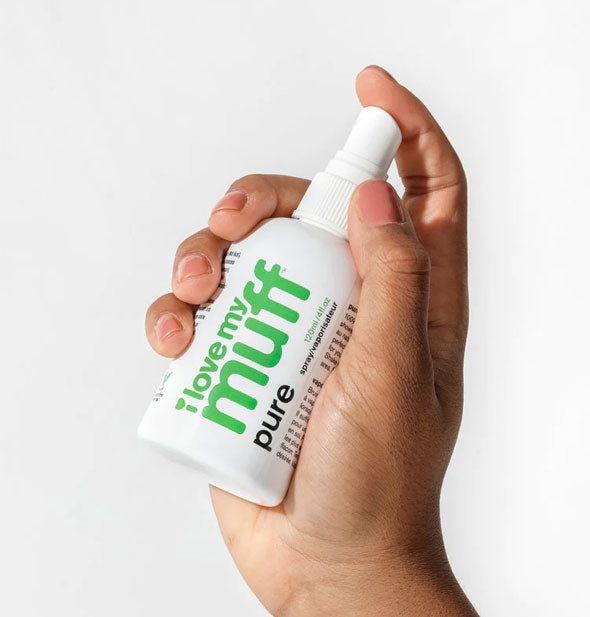 Model's hand holds a bottle of I Love My Muff Pure Spray with index finger on the nozzle