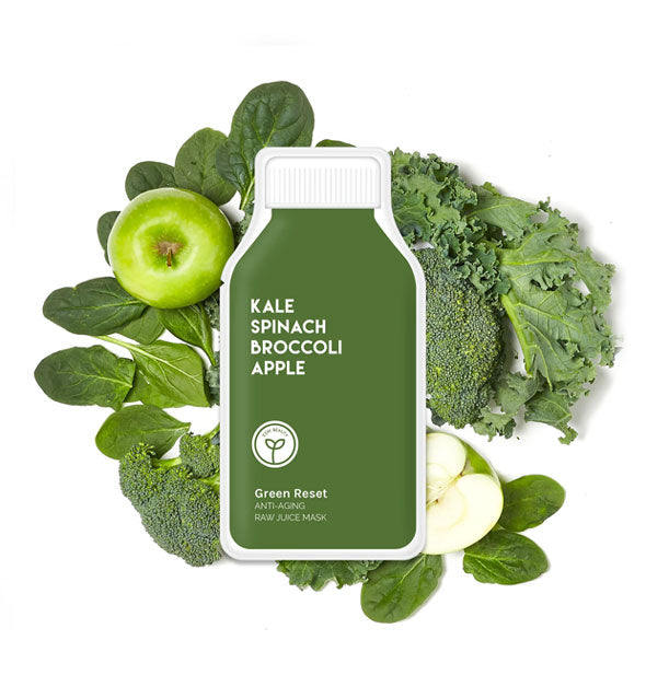 Green bottle-shaped Green Reset sheet mask pack rests on top of spinach leaves, broccoli florets, kale leaves, and green apple pieces