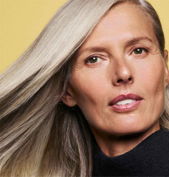 Model with healthy-looking gray hair demonstrates the results of using Oribe's Hair Alchemy products