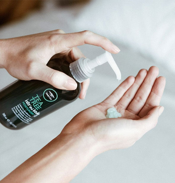 Model dispenses a pump of Paul Mitchell Tea Tree Hair and Body Moisturizer into palm of hand
