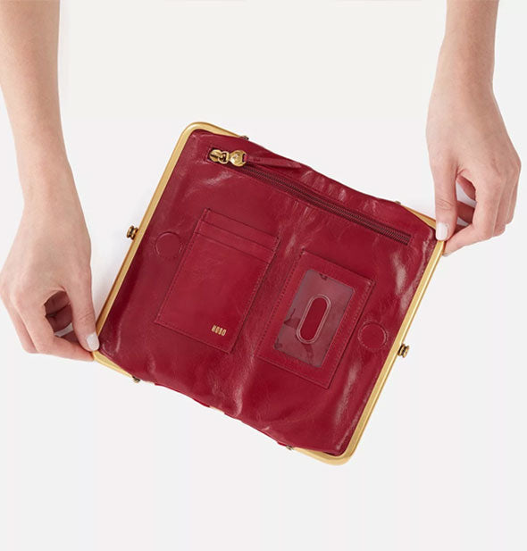 Model holds open a red leather wallet to reveal storage pockets inside