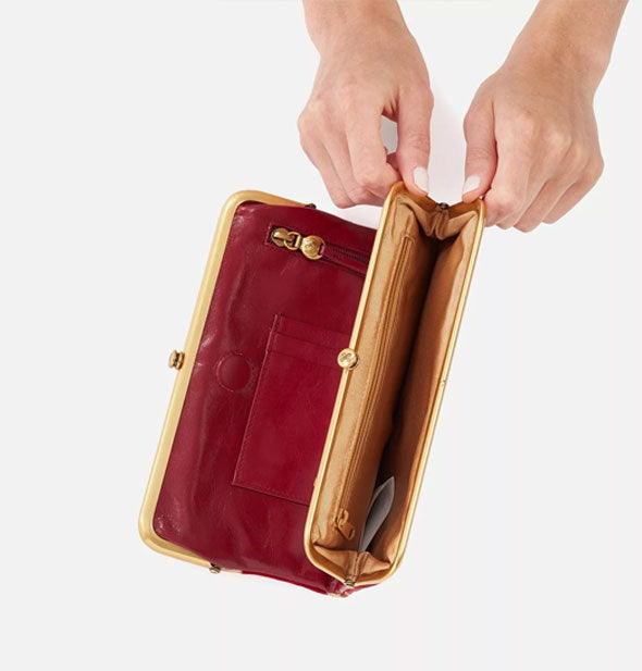 Model's hands hold open a red leather wallet frame compartment to reveal interior storage