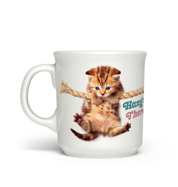 White coffee mug with image of a striped kitten hanging on a rope says, "Hang in There!" in green and pink lettering