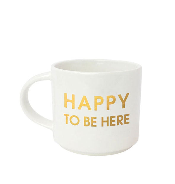 White coffee mug says, "Happy to Be Here" in metallic gold foil lettering