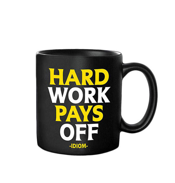 Black coffee mug is printed in white and yellow with the idiom, "Hard work pays off"