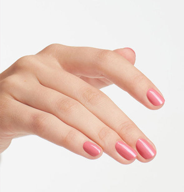 Model's hand wears a light pearly-pink shade of nail polish