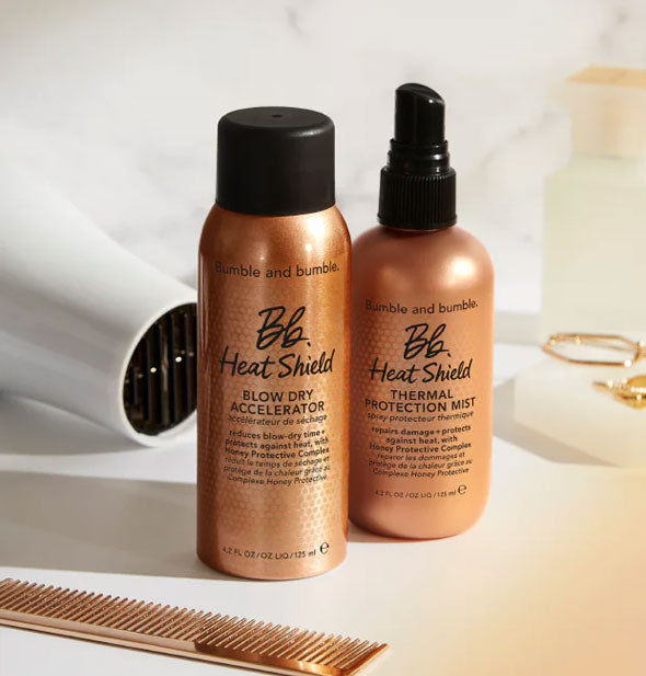 Bottles of Bumble and bumble Heat Shield Blow Dry Accelerator and Thermal Protection Mist on a marble countertop with other styling items