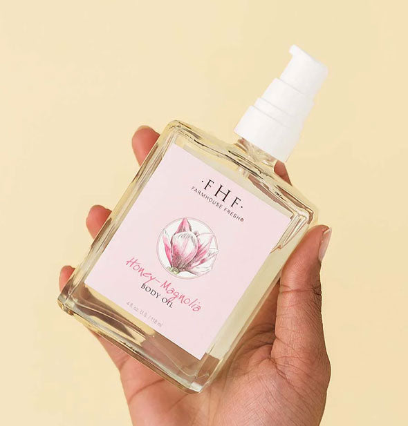 Model's hand holds a square glass bottle of FarmHouse Fresh Honey-Magnolia Body Oil