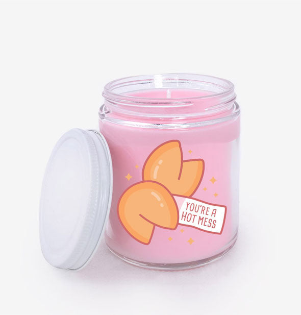 Jar candle with pink wax and white lid removed features illustration of two fortune cookies and the message, "You're a hot mess"