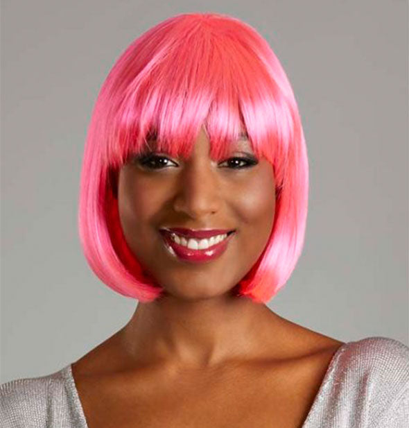 Model wearing a short, pink wig with bangs.