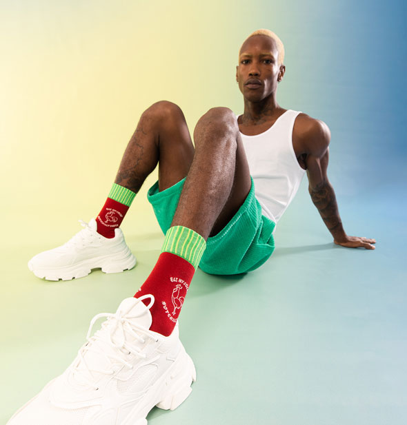 Seated model wears a pair of red and green Hot Sauce socks
