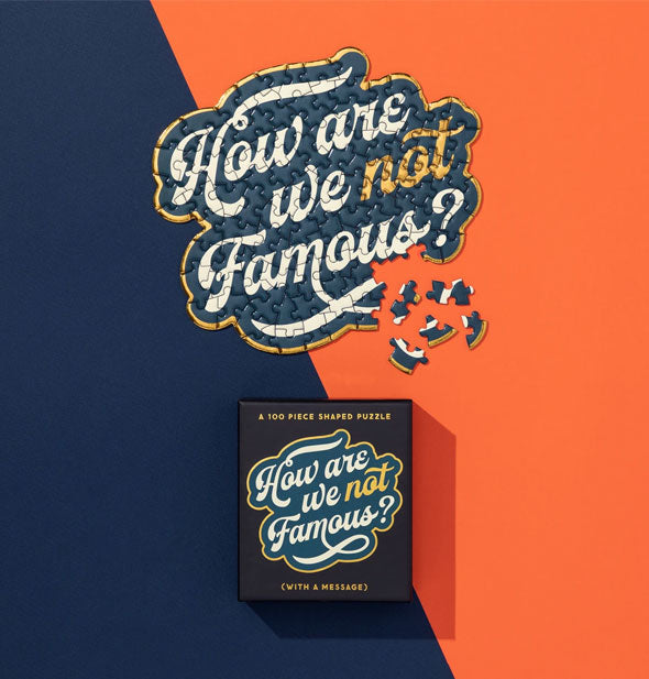 "How Are We Not Famous?" jigsaw puzzle shown mostly assembled with box on navy and orange background