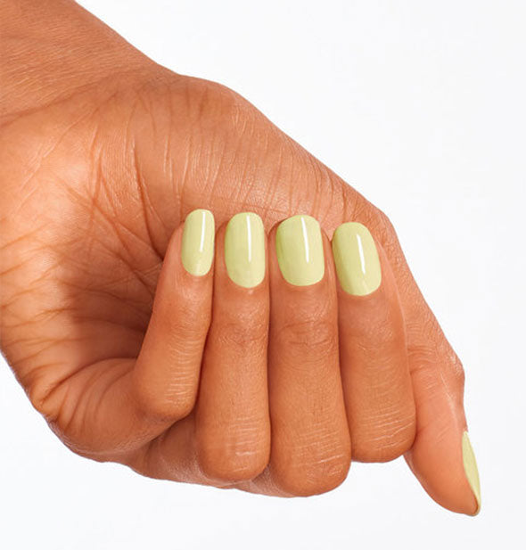 Model's hand wears a light pastel green shade of nail polish