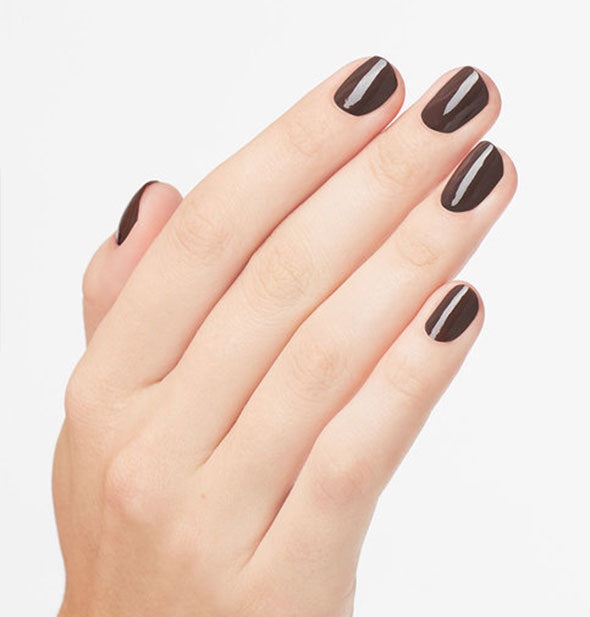 Model's hand wears a dark brown shade of nail polish