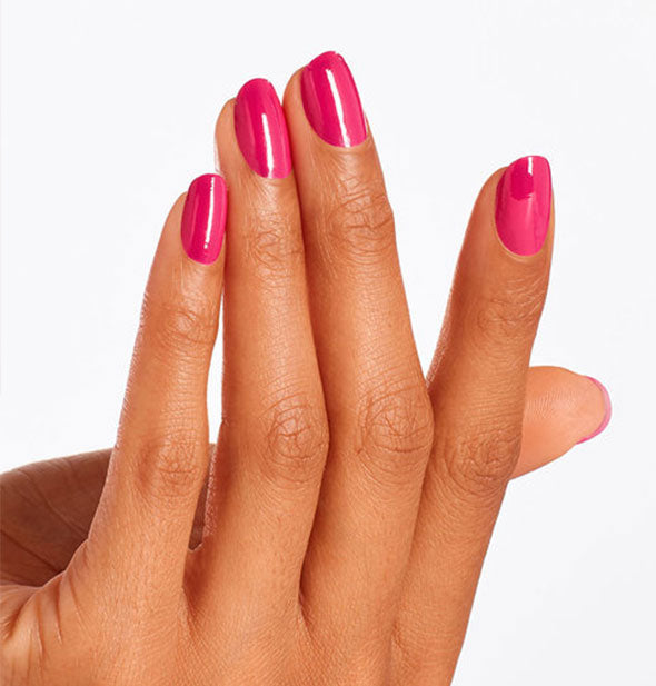 Model's hand wears a berry pink shade of nail polish