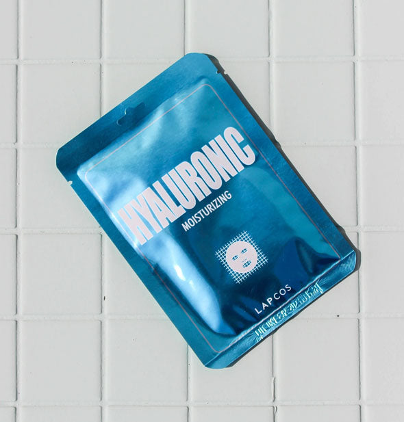 Shiny blue LAPCOS Hyaluronic Moisturizing sheet mask packet on a white tile surface