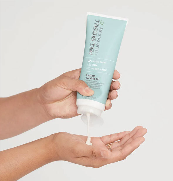 Model pours Paul Mitchell Clean Beauty Hydrate Conditioner from bottle into hand