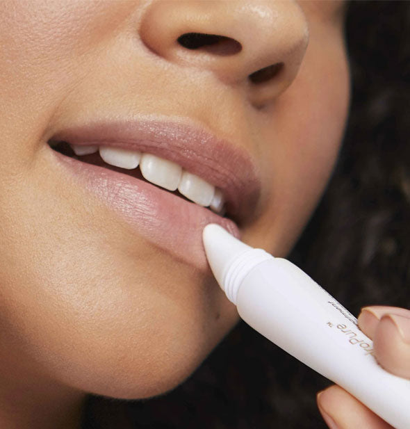 Model applies a Jane Iredale lip treatment to lower lip