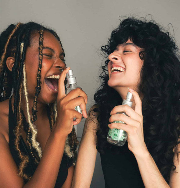 Two smiling models hold and spray bottles of Somebody brand hydrosol mist