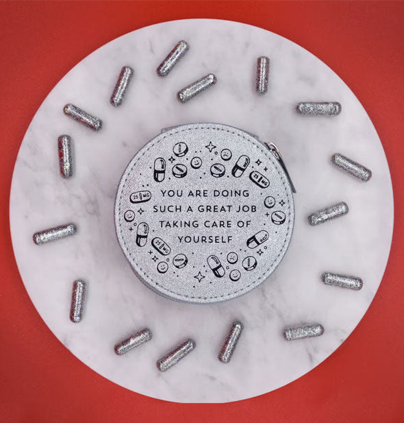 Round silvery-blue shimmery pill case on round marble pedestal scattered with glittery silver capsules says, "You are doing such a great job taking care of yourself" surrounded by small pill, capsule, and star graphics