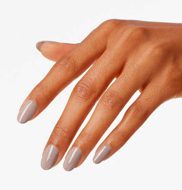 Model's hand wears a taupe shade of nail polish