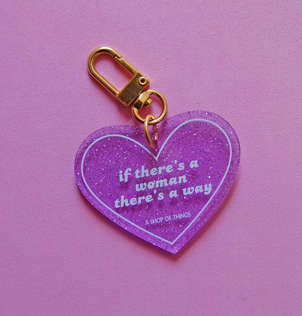 Heart-shaped purple glitter keychain with gold clasp says, "If there's a woman there's a way" in white lettering