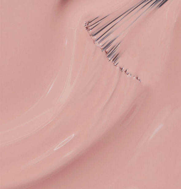 Dusty rose-pink nail polish with brush tip drawn through it