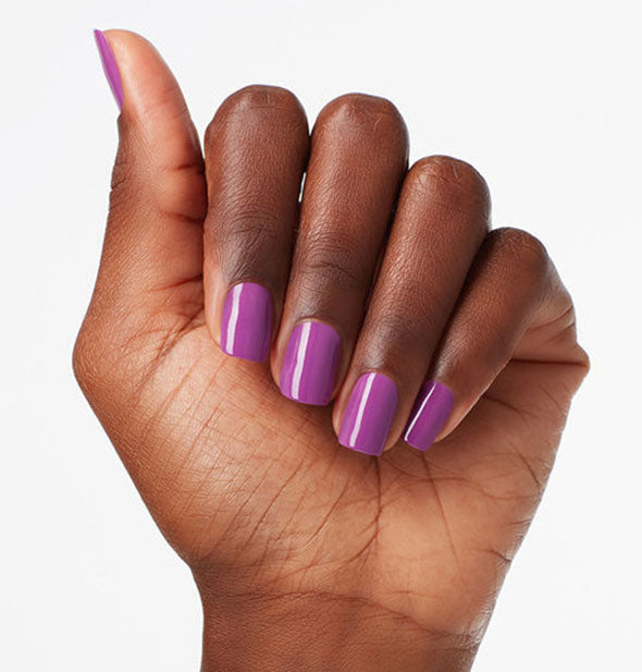 Model's hand wears a purple shade of nail polish