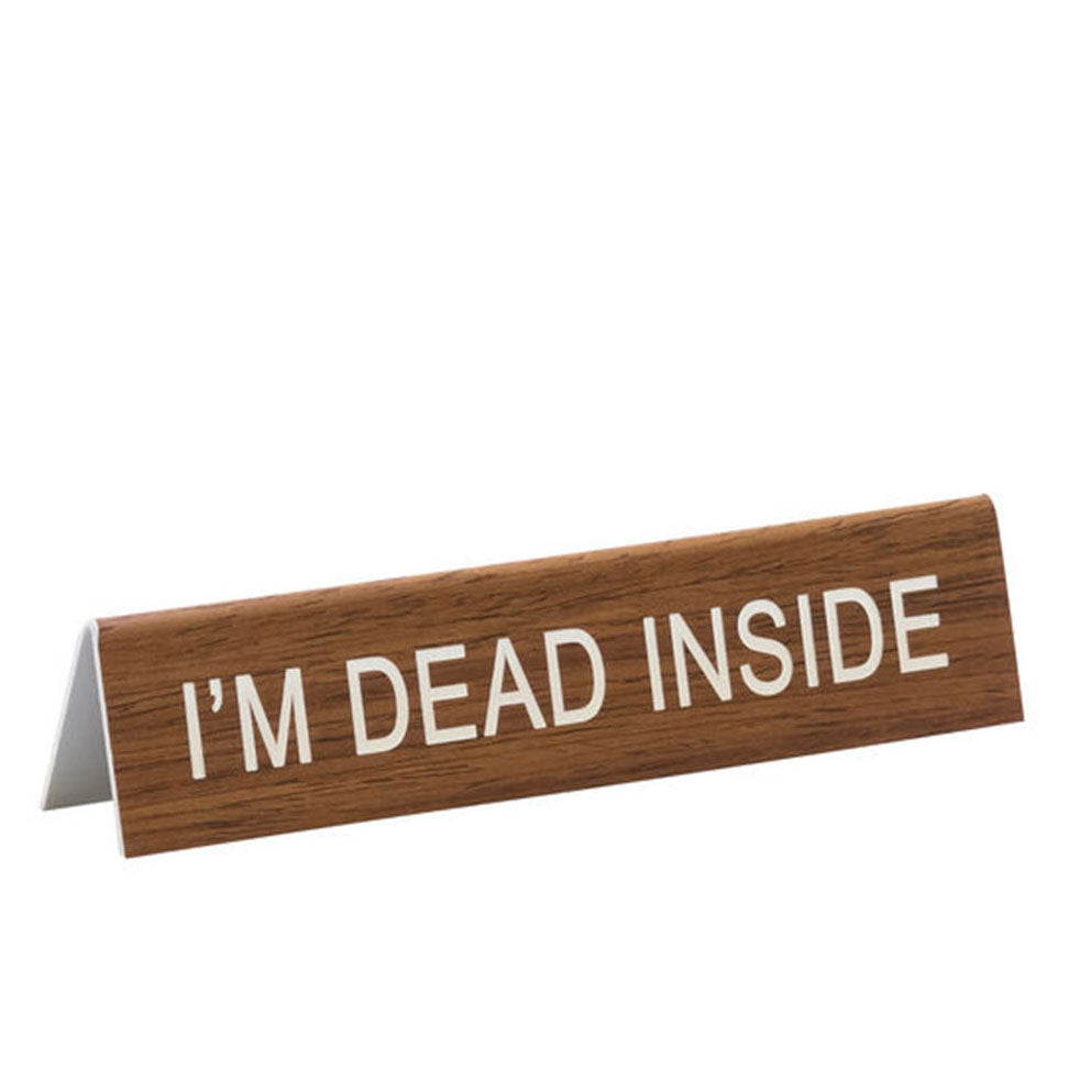 Rectangular faux wood desk placard says, "I'm dead inside" in white lettering