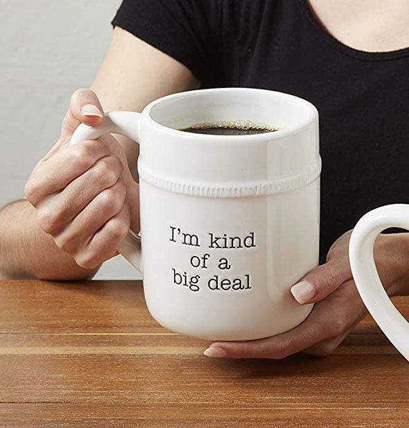 Model holds an oversized ceramic mug stamped with the words, "I'm kind of a big deal"