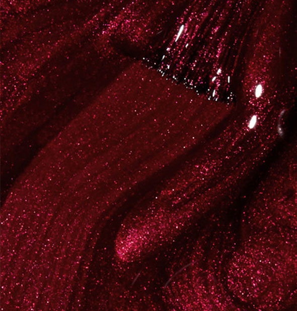 Shimmering red nail polish with brush tip drawn through it