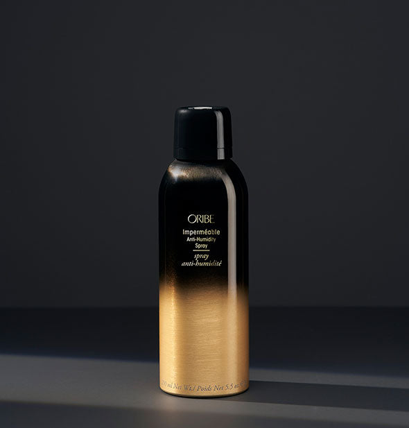 Black and gold can of Oribe Imperméable Anti-Humidity Spray on a dark gray background
