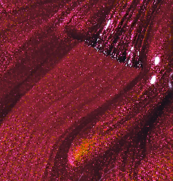 Shimmering red-gold nail polish with brush tip swiped through it
