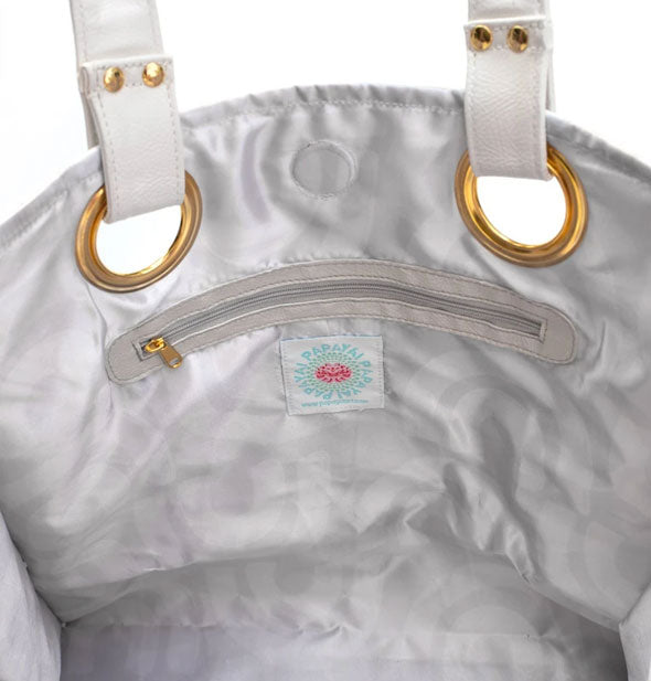 Tote bag interior with silver lining, zipper pocket, and gold handle hardware