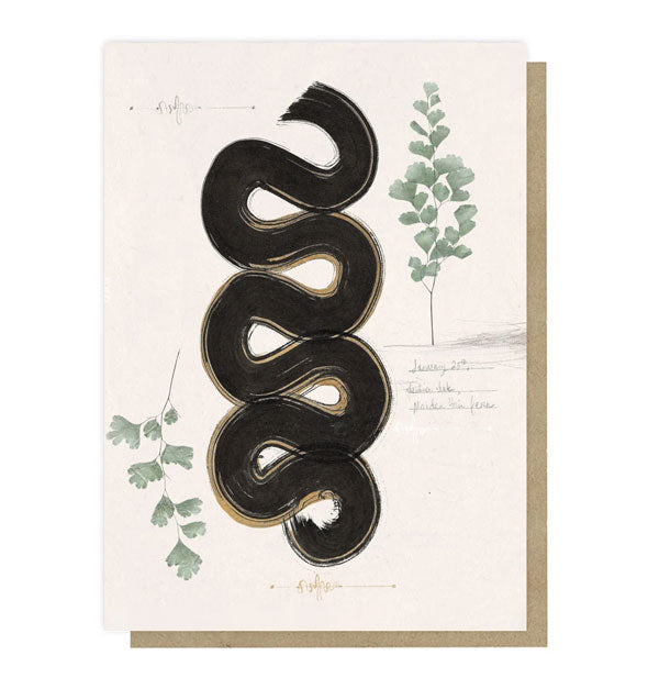 Cream-colored greeting card with kraft envelope behind features a snake-like black brushstroke design flanked by pressed leaves