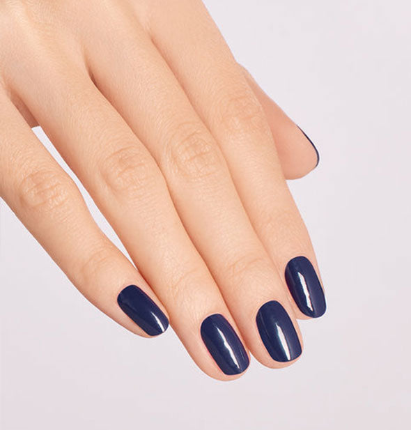 Model's hand wears a dark blue shade of nail polish