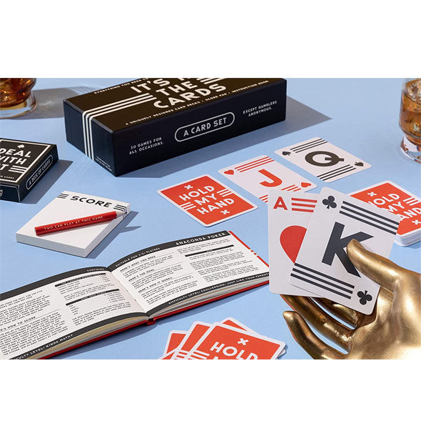 Components of the It's in the Cards game set spread out on a blue surface