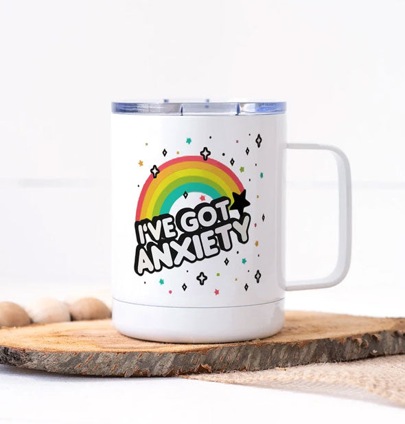 White travel mug with clear plastic lid features rainbow illustration with the words, "I've Got Anxiety"
