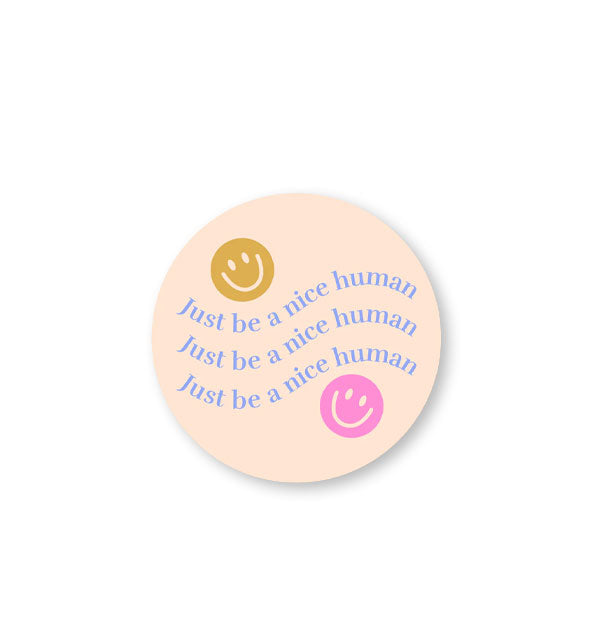Round light peach-colored sticker says, "Just be a nice human" three times in blue lettering flanked by two smiley face graphics in gold and pink