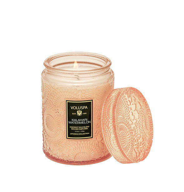 Peach-colored embossed glass Kalahari Watermelon Voluspa candle with matching lid set to the side