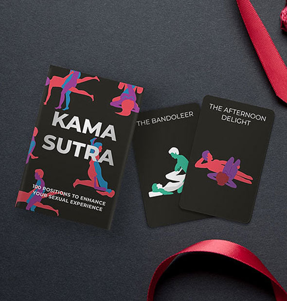 Sample cards from the Kama Sutra deck with box on a dark surface with red satin ribbon