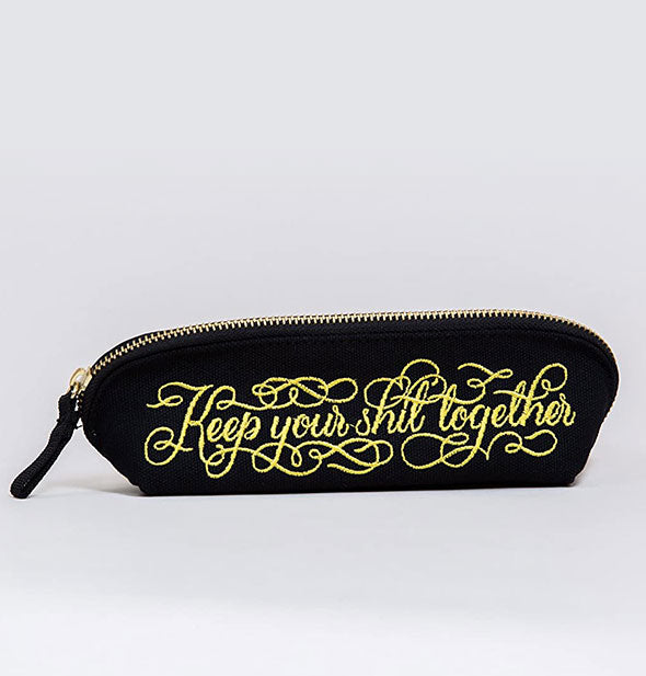 Elongated black pouch with zipper says, "Keep your shit together" in decorative gold embroidery