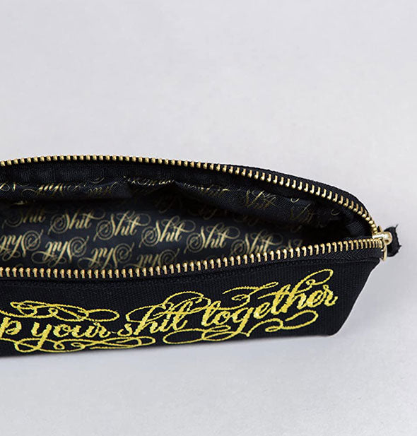 Pouch interior features "Shit" repeated in gold script on a black background
