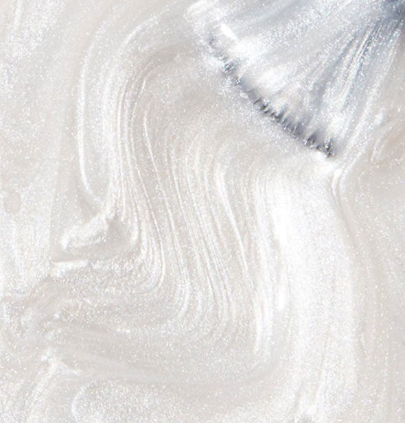 Shimmering pearlescent white nail polish with brush tip drawn through it