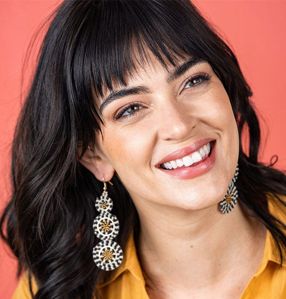 Smiling model wears a pair of circle design beaded earrings