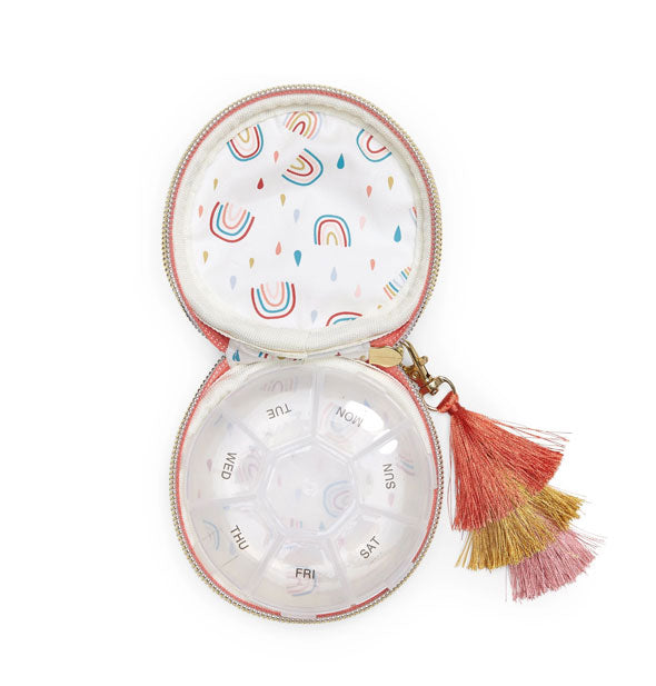 Open pill case with rainbow print lining and sectioned plastic insert with printed days of the week; tricolor tassel zipper pull extends out to the right