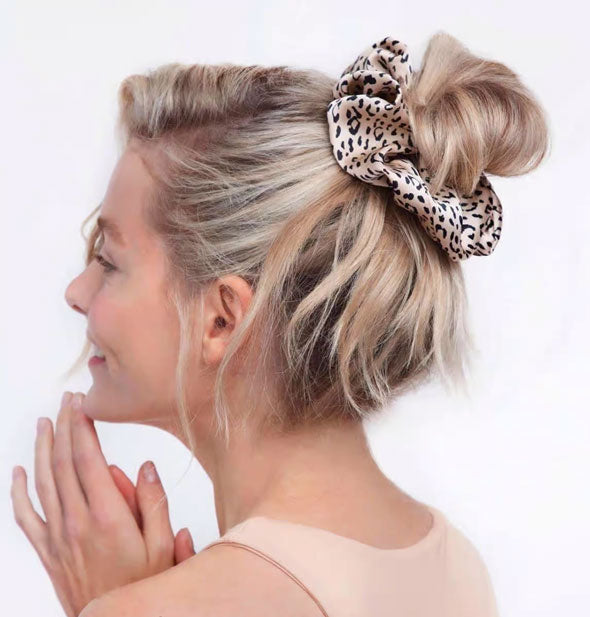 Smiling model wears a leopard print hair scrunchie in a messy topknot