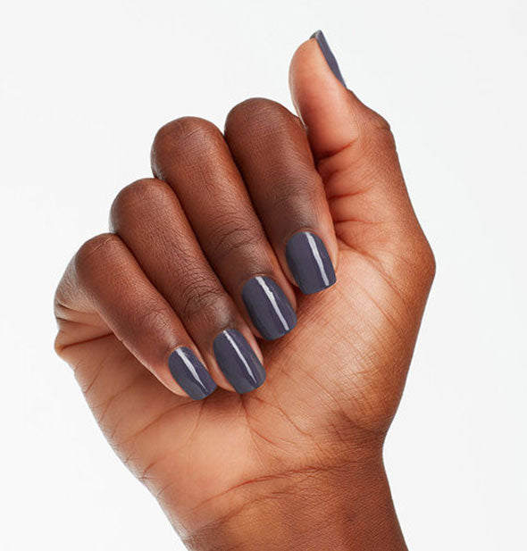 Model's hand wears a dark shade of gray-blue nail polish