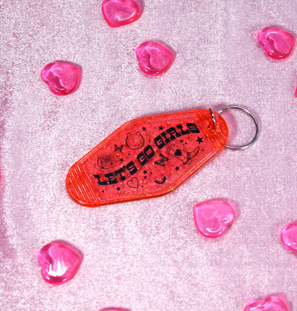 Clear red acrylic motel-style keychain with glitter finish says, "Let's Go Girls" in black lettering surrounded by heart, butterfly, star, and cowgirl-themed graphics